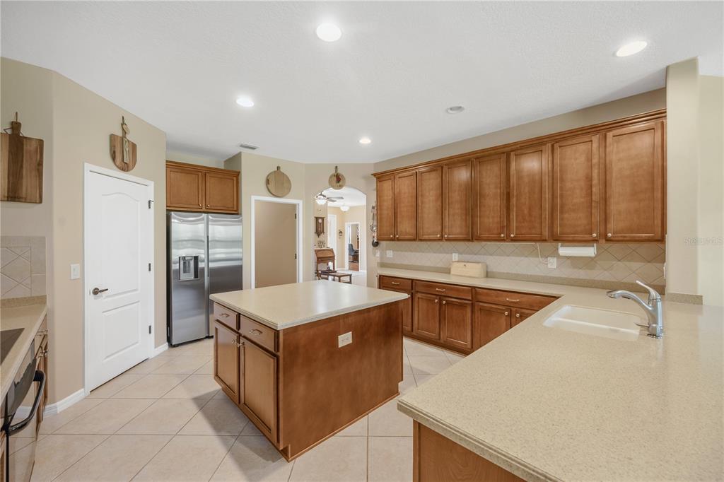 A kitchen features wood cabinets, a central island, beige countertops, and tile flooring — 9313 LISBON STREET, SEFFNER, FL