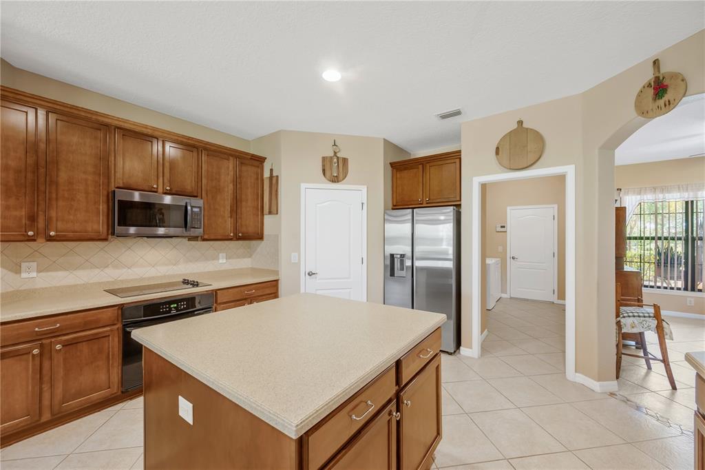 A kitchen with wood cabinets, stainless steel appliances, a center island, and tile flooring — 9313 LISBON STREET, SEFFNER, FL
