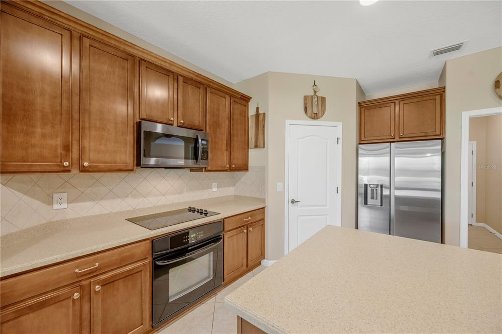 A kitchen features wood cabinets, stainless steel appliances, a center island, and beige countertops — 9313 LISBON STREET, SEFFNER, FL