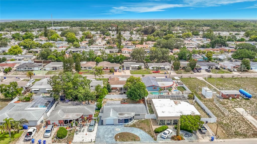 An aerial view shows several single-story residential homes with driveways and backyards in a neighborhood — 3441 EISENHOWER DRIVE, HOLIDAY, FL