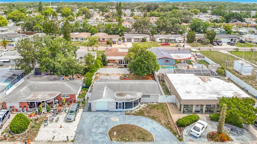An aerial view shows a residential neighborhood with single-story houses, driveways, and surrounding trees — 3441 EISENHOWER DRIVE, HOLIDAY, FL