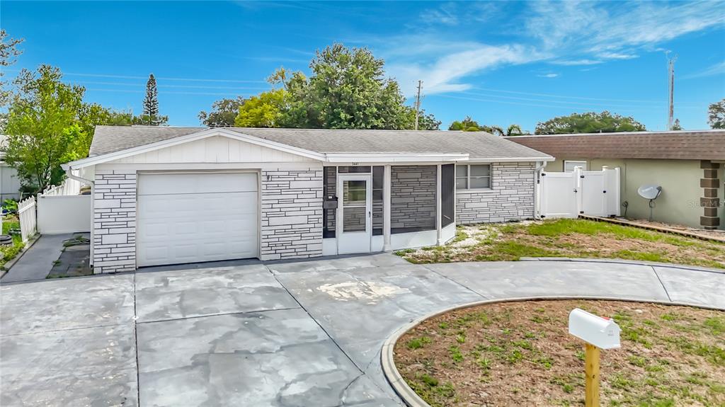 A single-story house with a white garage door, stone facade, and a curved concrete driveway — 3441 EISENHOWER DRIVE, HOLIDAY, FL