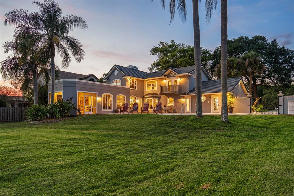 A two-story house with a gray exterior, arched windows, and a large grassy backyard — 9620 MAYWOOD DRIVE, WINDERMERE, FL