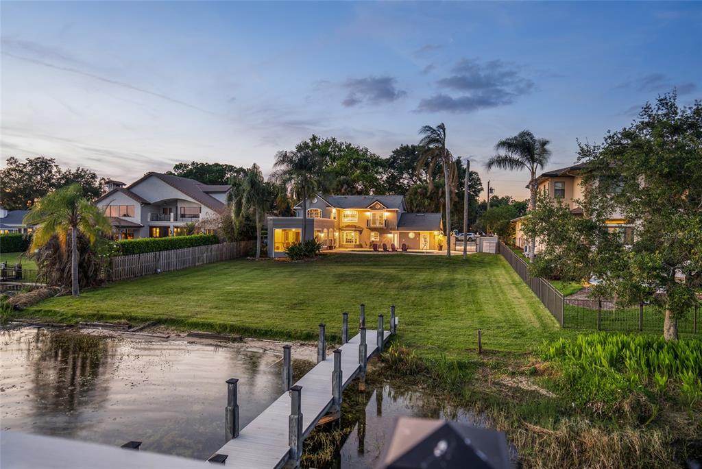 A large house with a backyard lawn and a wooden dock extending into a lake — 9620 MAYWOOD DRIVE, WINDERMERE, FL