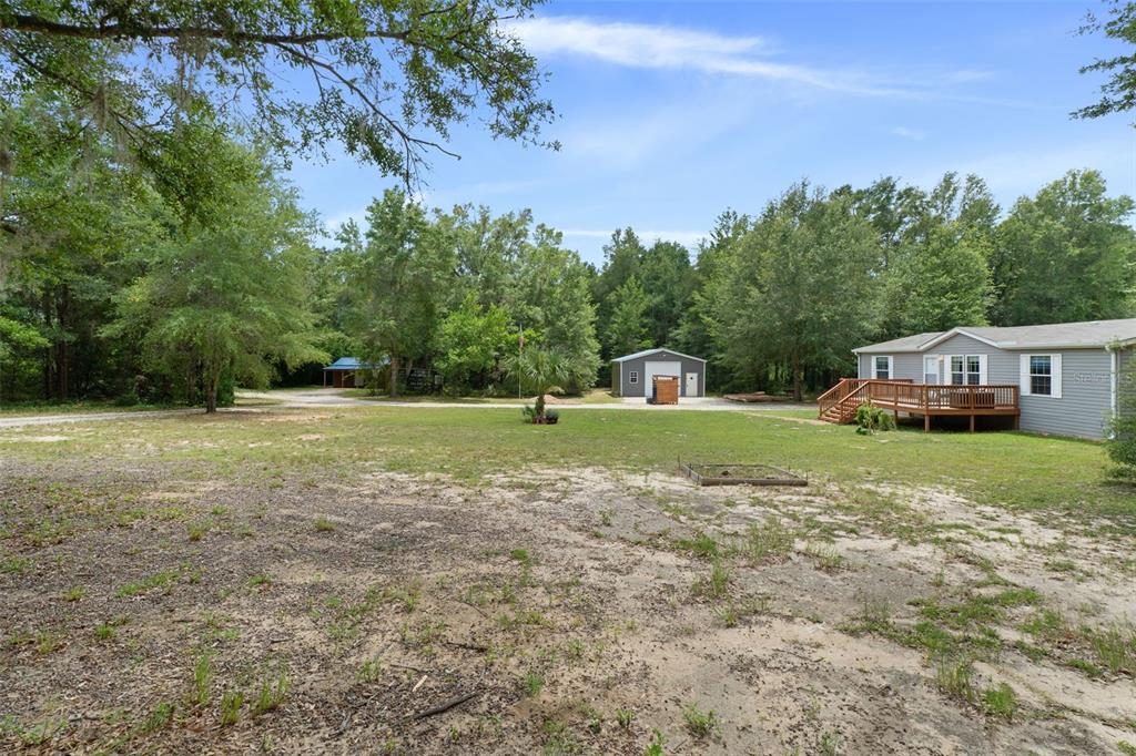 A grassy yard with a house, a detached garage, and surrounding trees — 840 N OBRIEN POINT, LECANTO, FL