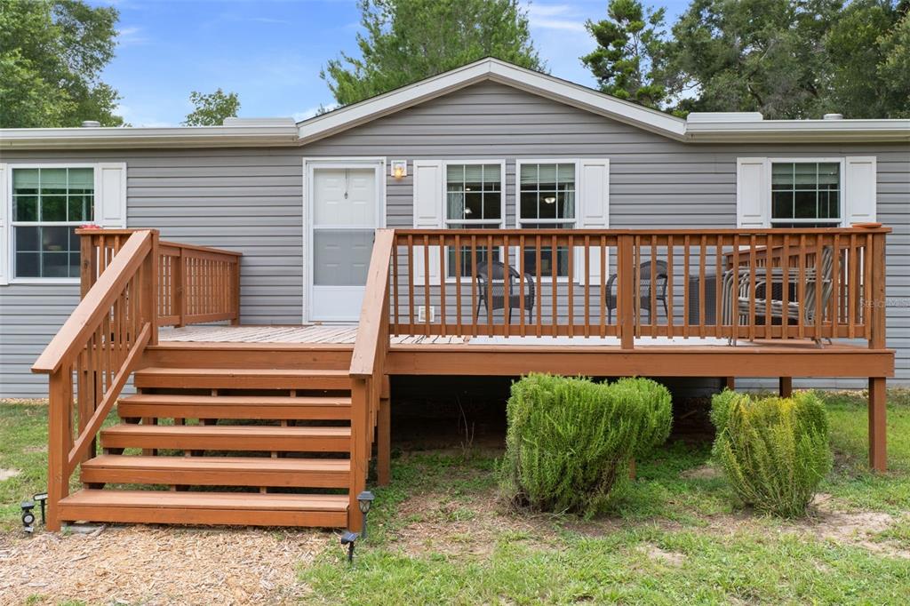 A gray mobile home features a wooden deck with stairs and two small green bushes — 840 N OBRIEN POINT, LECANTO, FL