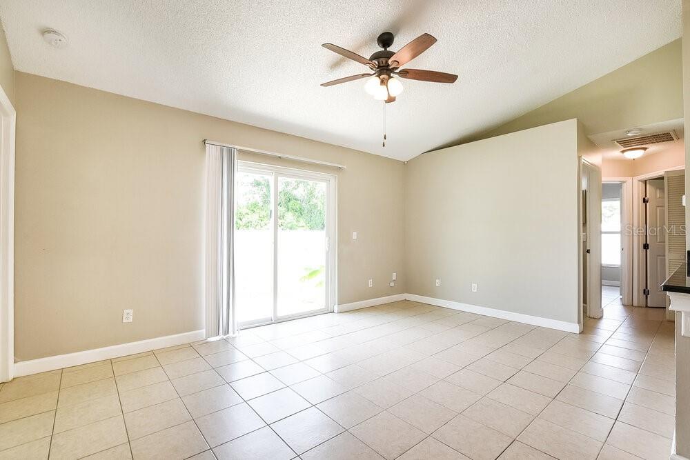 An empty room with beige walls, tile flooring, a ceiling fan, and sliding glass doors — 1306 SILVERTHORN DRIVE, ORLANDO, FL
