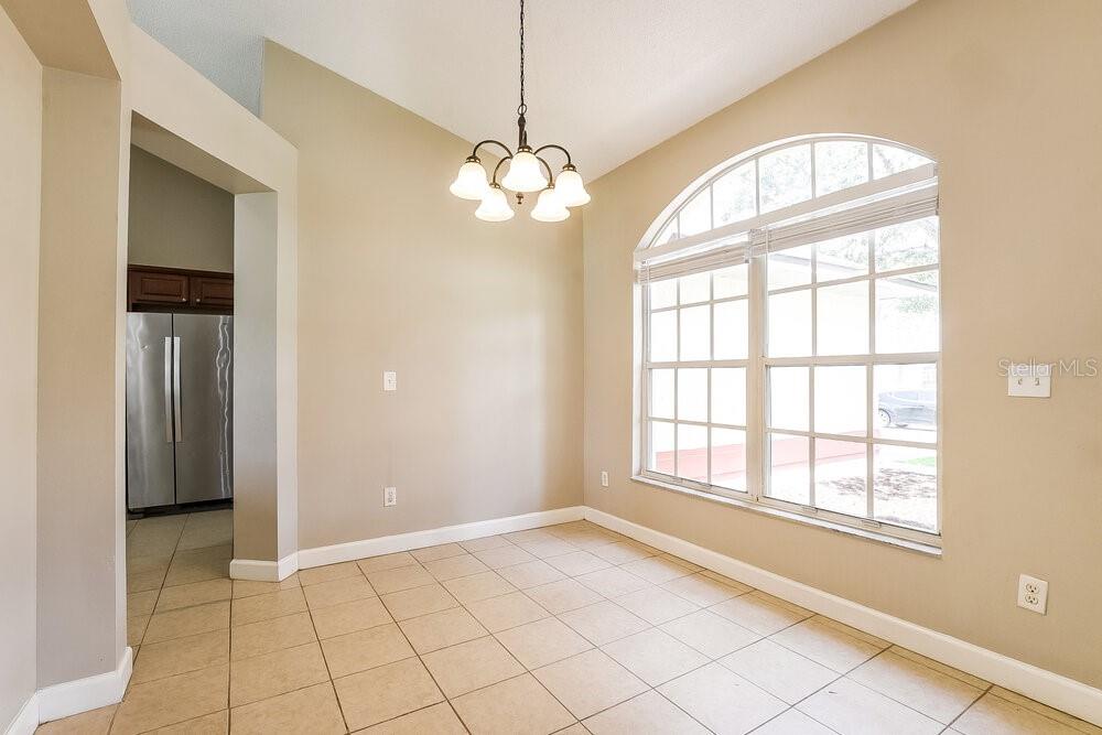 A dining area with tile flooring, a chandelier, and a large arched window — 1306 SILVERTHORN DRIVE, ORLANDO, FL