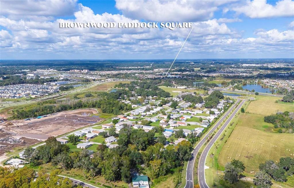 An aerial view shows a residential neighborhood, a road, and undeveloped land near a town center — LOT 26 BLK D STRATFORD COURT, WILDWOOD, FL