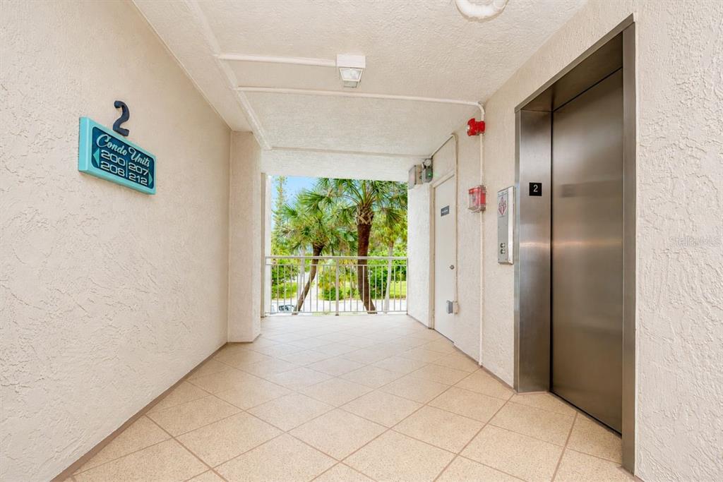A living room with tile floors, a ceiling fan, and sliding glass doors overlooking water — 200 1ST AVENUE UNIT 207, ST PETE BEACH, FL