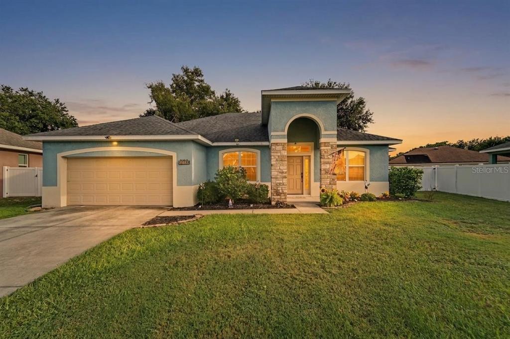 A single-story house with a blue stucco exterior, stone accents, and an attached two-car garage — 13144 LAUREL CREST COURT, GRAND ISLAND, FL
