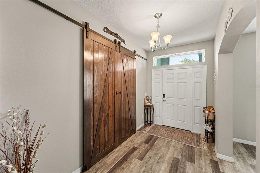 An entryway features wood-look flooring, a white front door, and large wooden sliding barn doors — 13144 LAUREL CREST COURT, GRAND ISLAND, FL