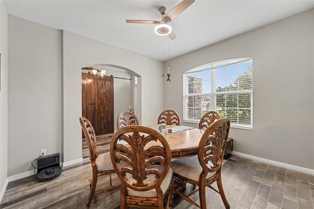 A dining room features a round wooden table with carved chairs, a ceiling fan, and flooring — 13144 LAUREL CREST COURT, GRAND ISLAND, FL