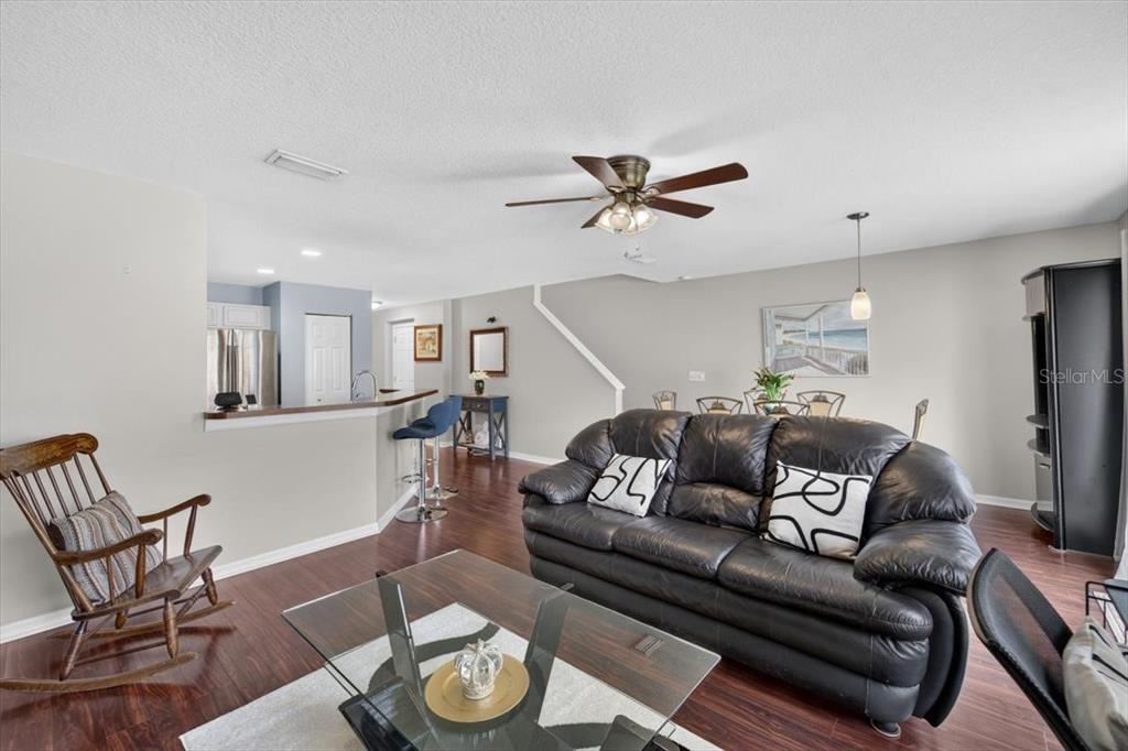 A living room with dark wood floors, a black leather sofa, and an open kitchen — 4582 LIMERICK DRIVE, TAMPA, FL