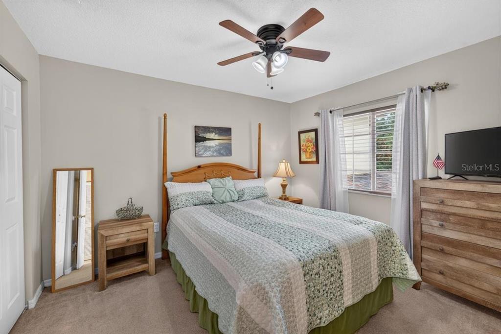 A bedroom features a wooden bed frame, a dresser, a ceiling fan, and a mirror — 4582 LIMERICK DRIVE, TAMPA, FL