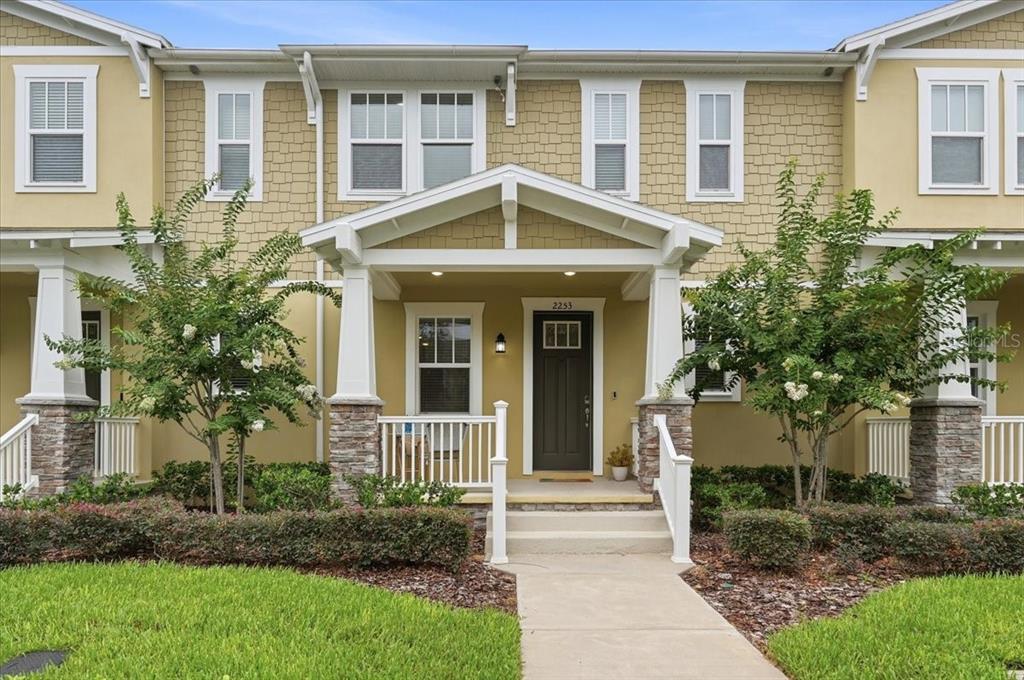A two-story townhouse exterior with tan siding, stone accents, and a covered front porch — 2253 CELEBRATION BOULEVARD, CELEBRATION, FL