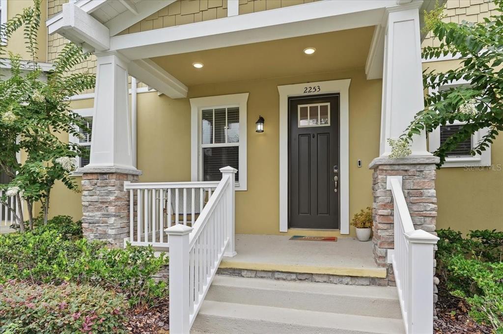 A covered front porch with stone-based pillars, white railings, and a dark brown front door — 2253 CELEBRATION BOULEVARD, CELEBRATION, FL