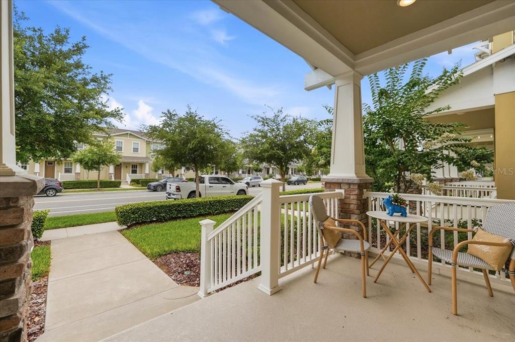 A covered front porch features white railings, two chairs, a small table, and stone columns — 2253 CELEBRATION BOULEVARD, CELEBRATION, FL