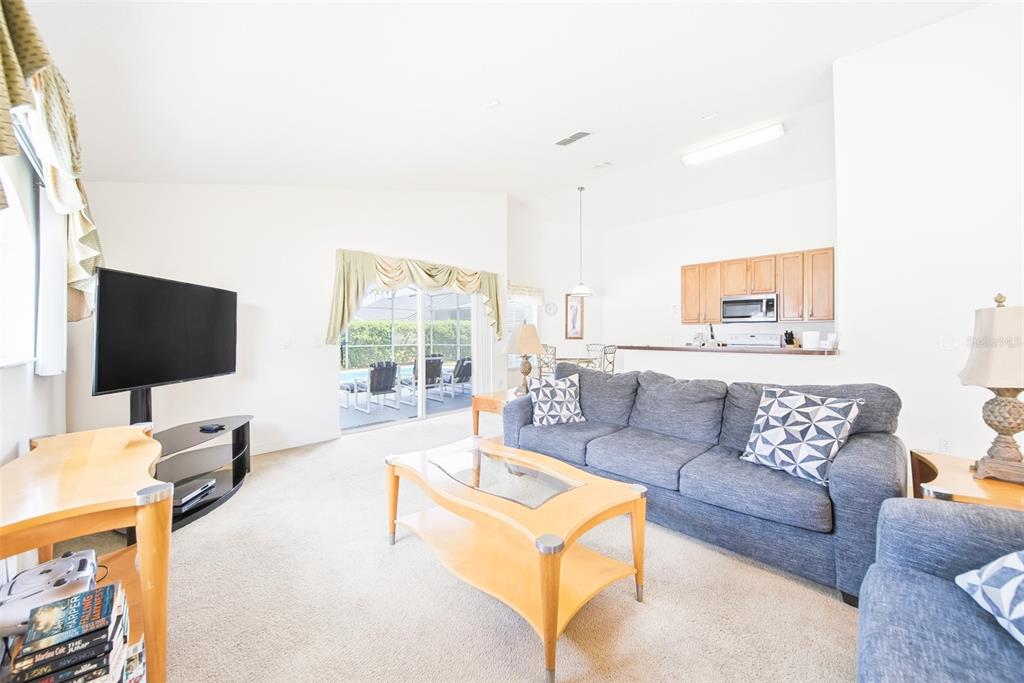 A living room features a grey sofa, a wooden coffee table, and a sliding door — 723 OLD BRIDGE CIRCLE, DAVENPORT, FL
