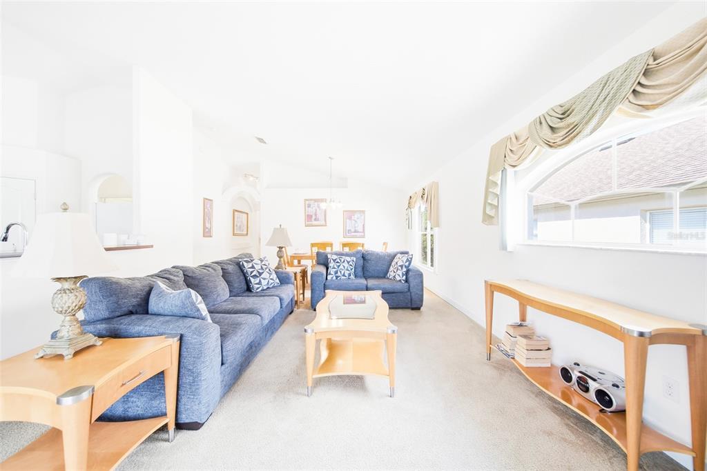 A living room features blue sofas, light wood furniture, and a large arched window — 723 OLD BRIDGE CIRCLE, DAVENPORT, FL