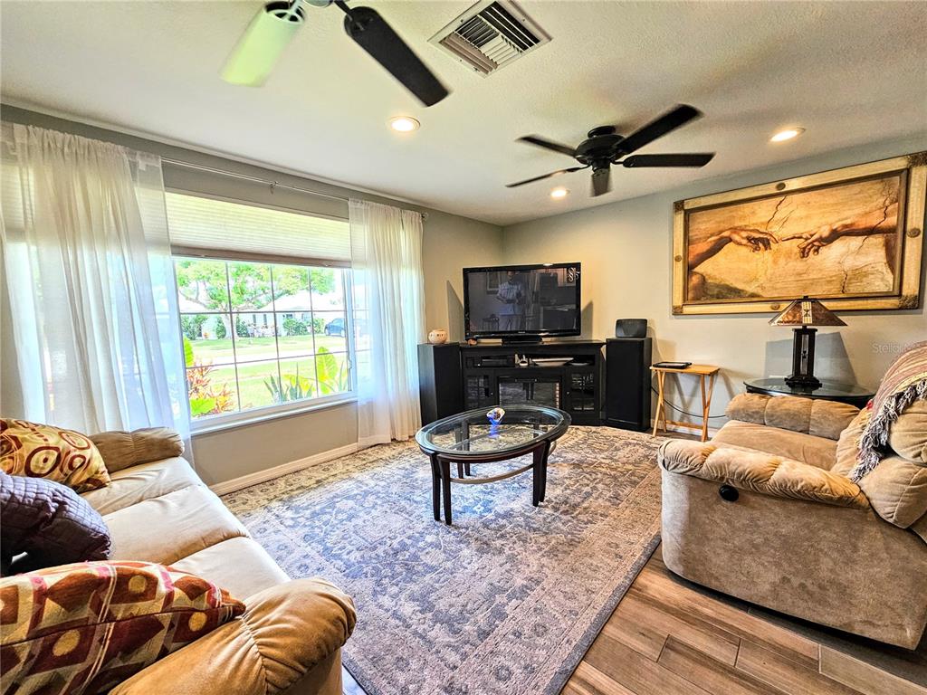 A living room features a large area rug, two sofas, a television, and ceiling fans — 5650 BITTERSWEET DRIVE, HOLIDAY, FL