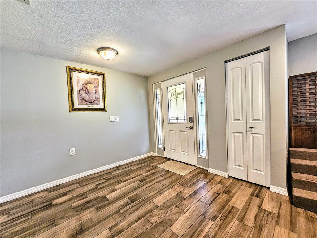 An entryway features wood-look flooring, a white front door with sidelights, and a closet — 5650 BITTERSWEET DRIVE, HOLIDAY, FL