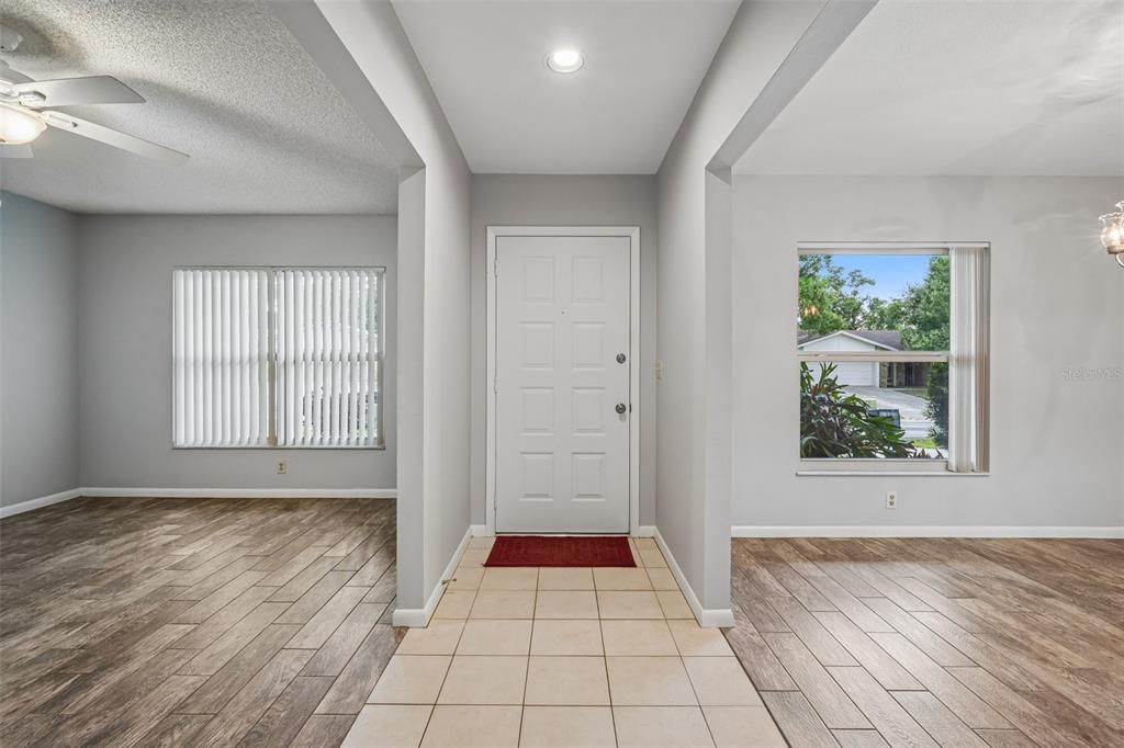 An entryway with a tiled floor leads to a white front door between two rooms — 3718 SAND PEBBLE DRIVE, VALRICO, FL