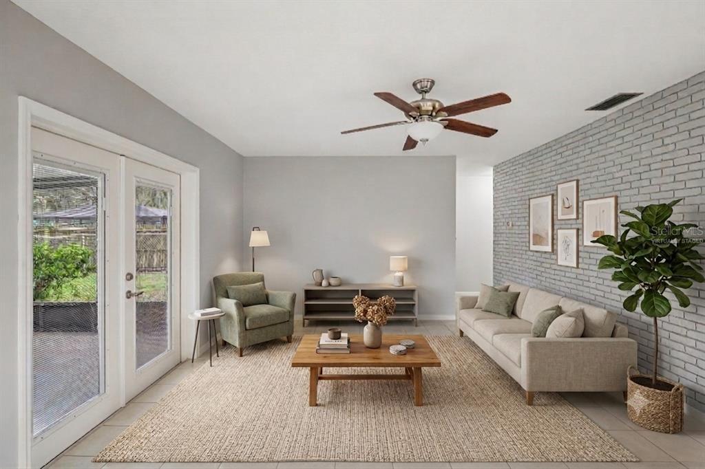 A living room features a gray brick accent wall, a beige sofa, and a glass door — 3718 SAND PEBBLE DRIVE, VALRICO, FL