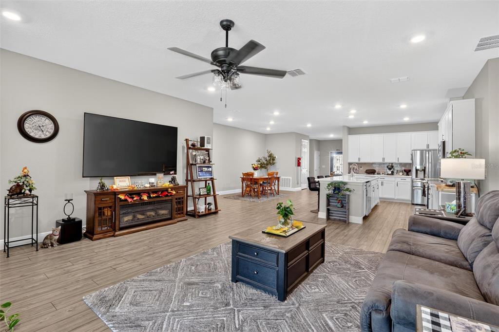 An open-concept living room and kitchen featuring wood-look tile flooring and a ceiling fan — 9839 SW 40TH TERRACE, OCALA, FL