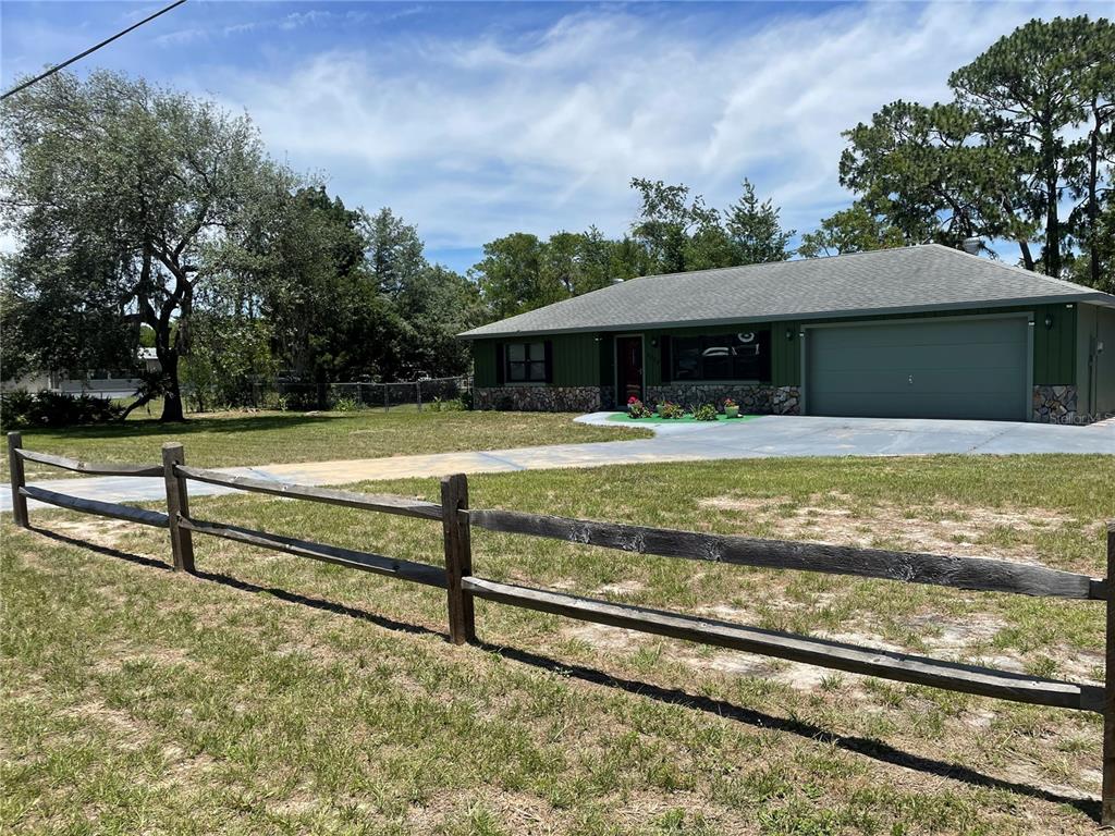 A single-story house with green siding, a stone base, and an attached garage — 7223 S SESAME STREET TERRACE, HOMOSASSA, FL