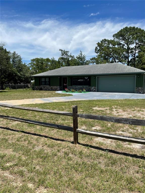A single-story house with a stone facade and a garage sits behind a large tree — 7223 S SESAME STREET TERRACE, HOMOSASSA, FL
