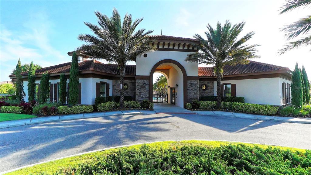 A Mediterranean-style clubhouse exterior features a central arched entryway, palm trees, and landscaped grounds — 1307 OAK CREST STREET, DAVENPORT, FL