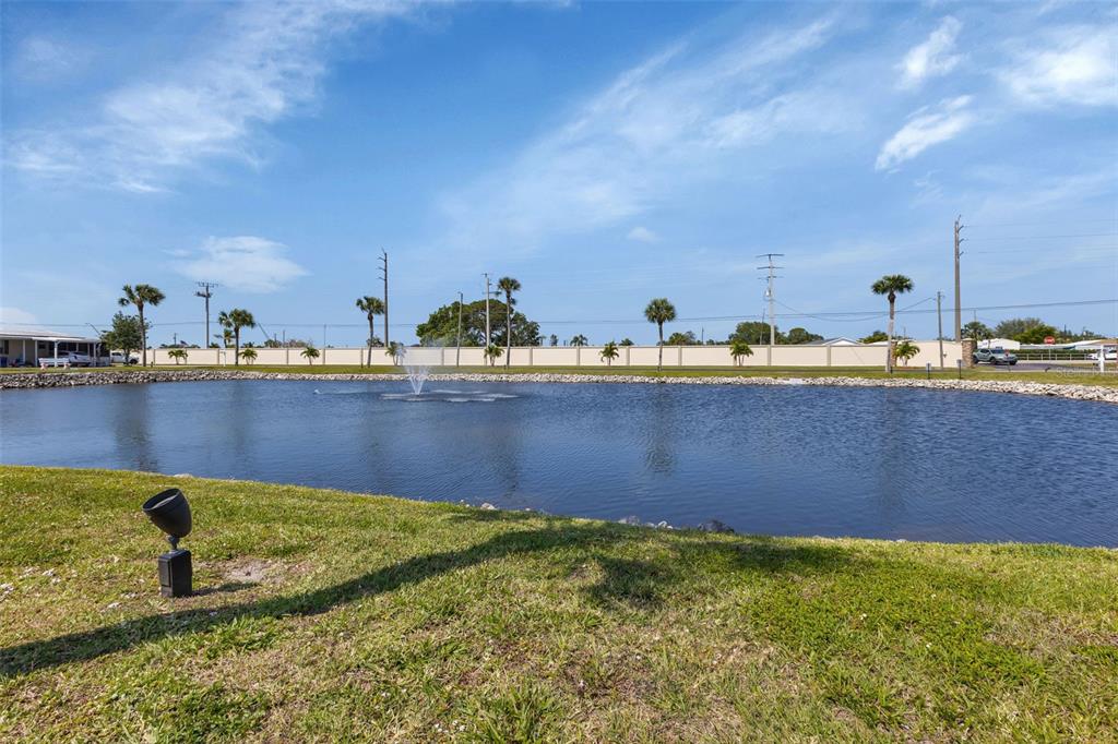 A grassy lawn overlooks a pond with a fountain and a perimeter wall in back — 10100 BURNT STORE ROAD UNIT 118, PUNTA GORDA, FL