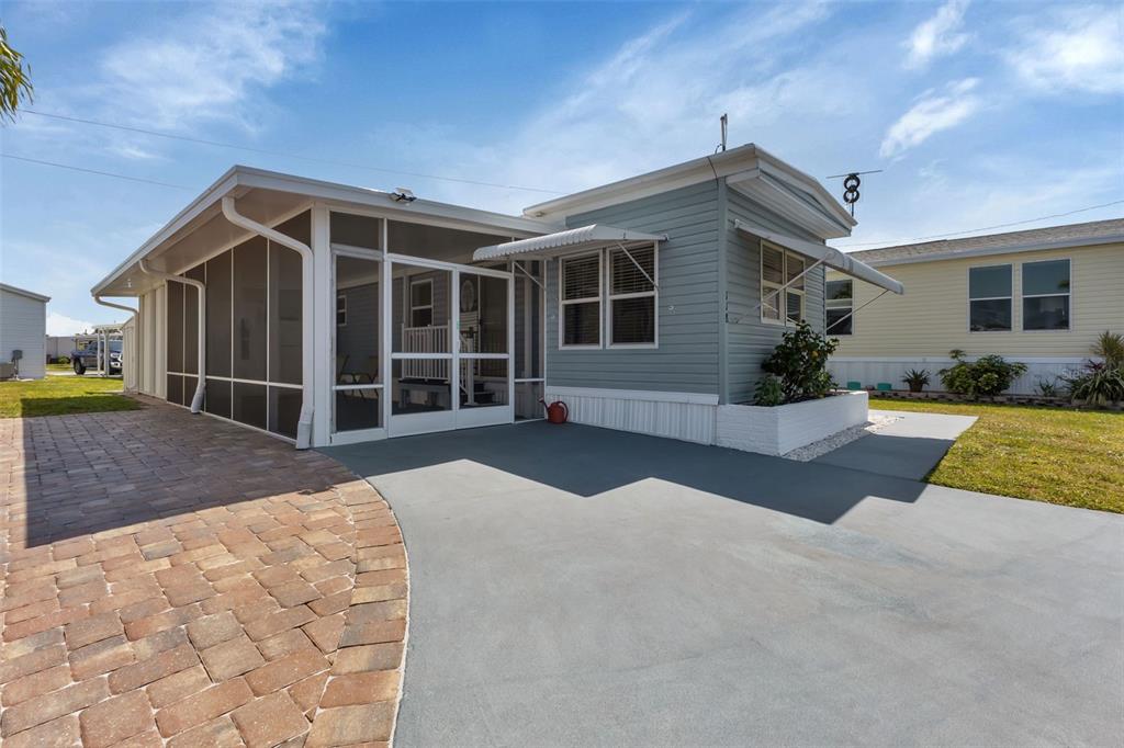 A light blue mobile home features a screened-in porch and a paved driveway — 10100 BURNT STORE ROAD UNIT 118, PUNTA GORDA, FL