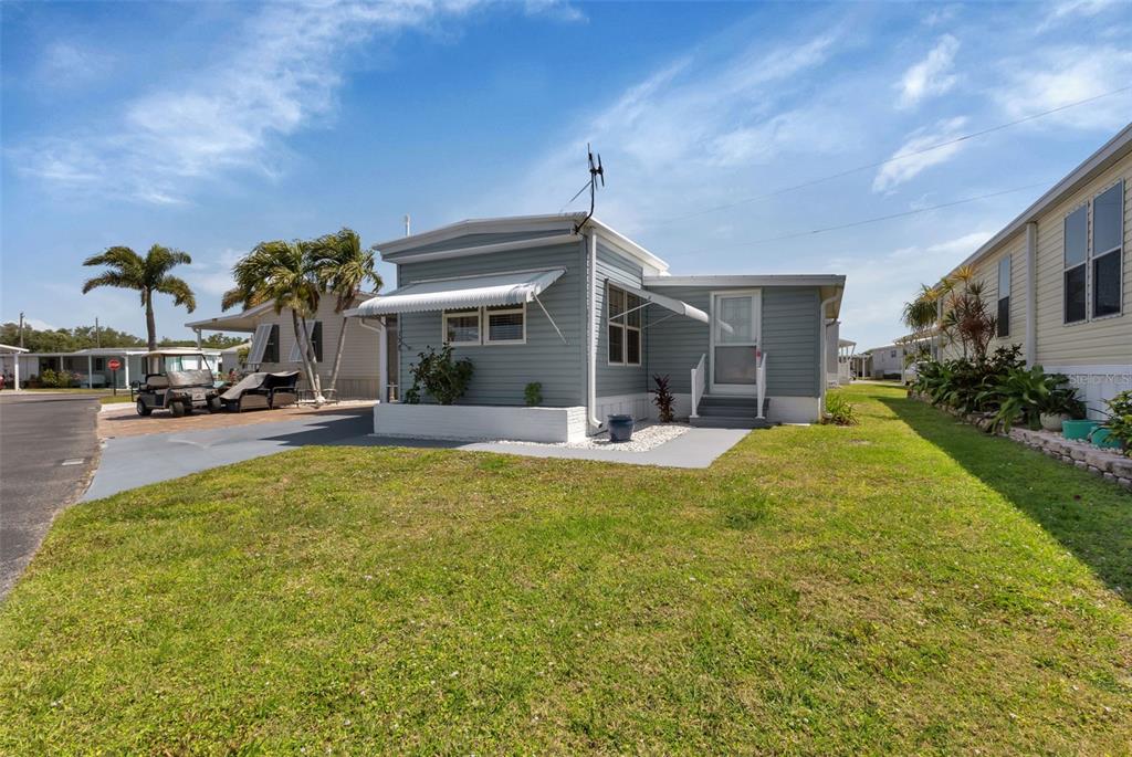 A light blue mobile home with a white awning and a small front yard — 10100 BURNT STORE ROAD UNIT 118, PUNTA GORDA, FL