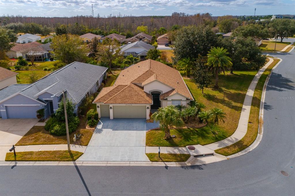 An aerial view shows a tan house with a brown roof on a corner lot — 20520 HOMOSSASA COURT, LAND O LAKES, FL