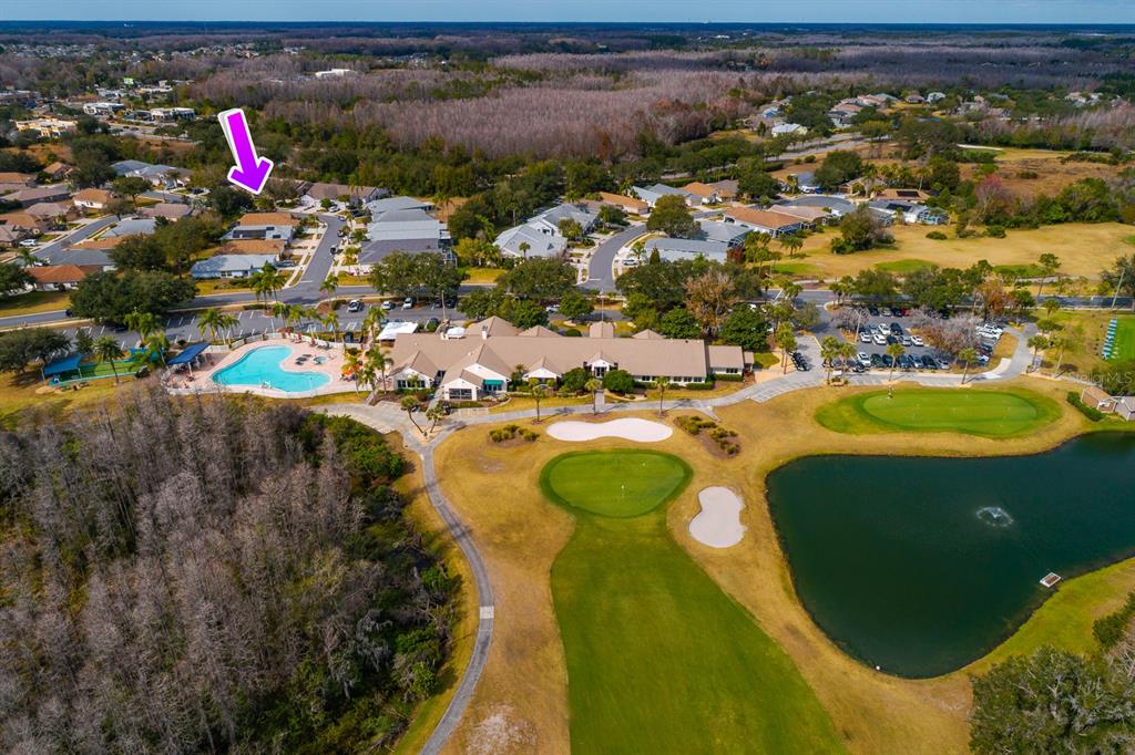An aerial view shows a residential community with a clubhouse, swimming pool, and golf course — 20520 HOMOSSASA COURT, LAND O LAKES, FL