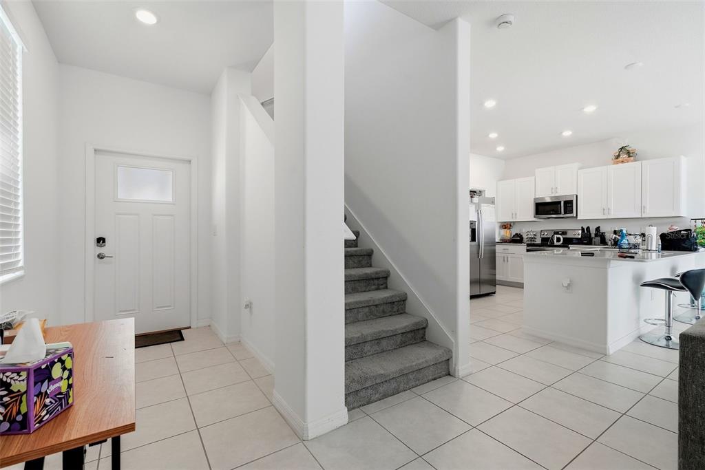 A view of an entryway with stairs leading to an open-concept kitchen and living area — 10336 LAVENDER ASTER TRAIL, SAN ANTONIO, FL