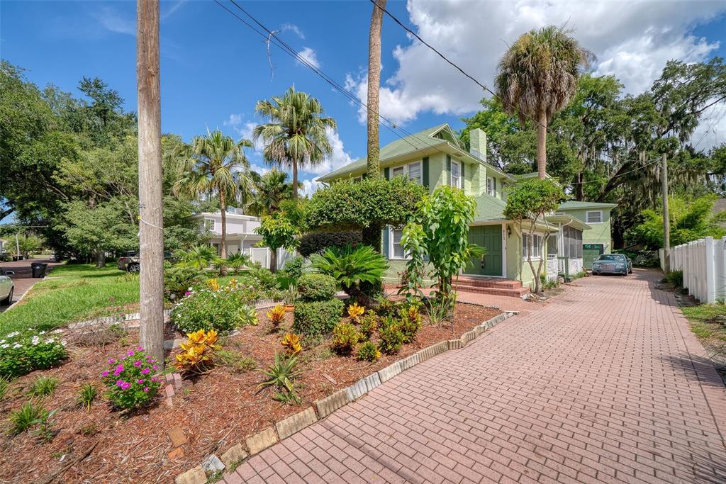 A two-story light green house features a brick driveway, palm trees, and a landscaped front yard — 813 GREENWOOD STREET, ORLANDO, FL