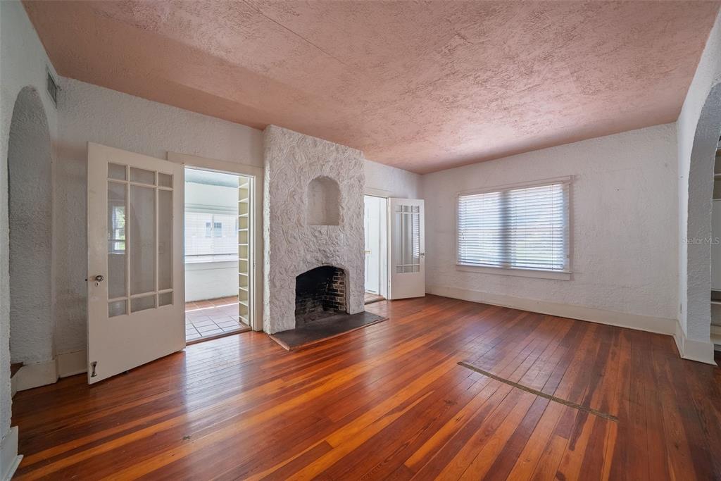 A living room features hardwood floors, a white textured fireplace, and a pink ceiling — 813 GREENWOOD STREET, ORLANDO, FL