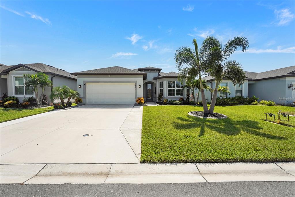 A single-story suburban house with a two-car garage, palm trees, and a manicured lawn — 2930 61ST DRIVE E, ELLENTON, FL