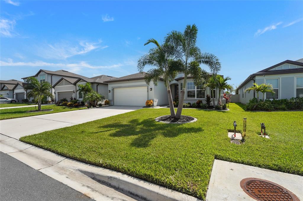 A single-story suburban house with a two-car garage, manicured lawn, and palm trees — 2930 61ST DRIVE E, ELLENTON, FL