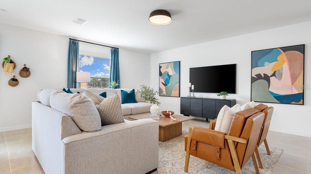 A living room features a light gray sectional sofa, two leather armchairs, and abstract wall art — 12206 WISPY CLOUD WAY, HUDSON, FL