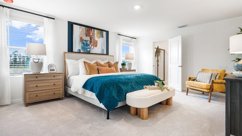 A bedroom features a bed with a teal quilt, a wooden dresser, and a yellow chair — 12206 WISPY CLOUD WAY, HUDSON, FL