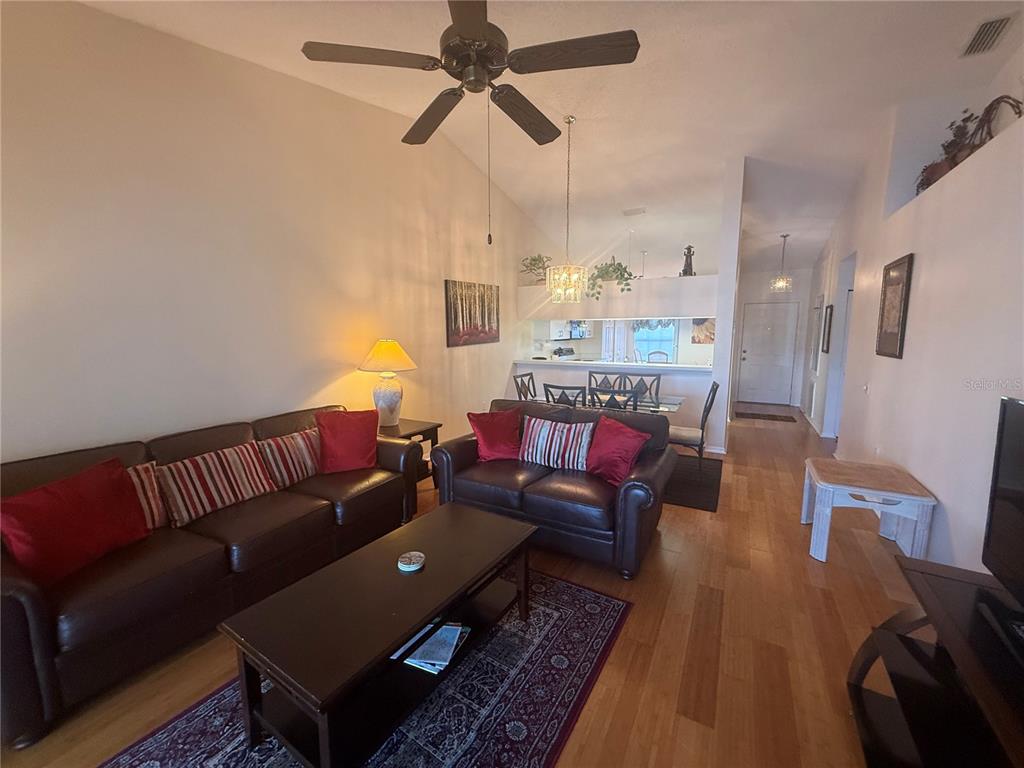 A living room with leather sofas, a coffee table, and an open dining area — 4211 CADDIE DRIVE E UNIT 202, BRADENTON, FL
