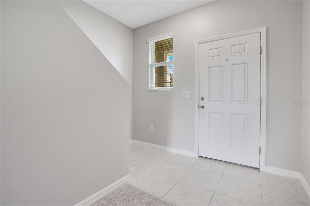 An entryway features light gray walls, white tile flooring, a window, and a white front door — 1068 APPLETON STREET, DAVENPORT, FL