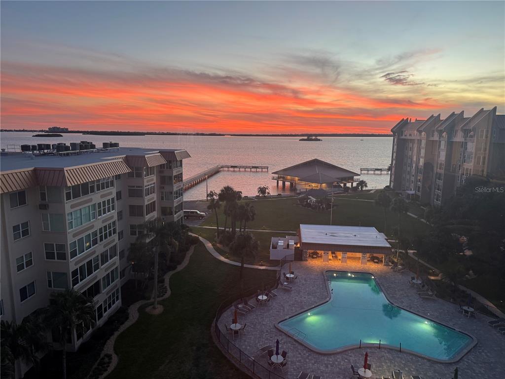 An elevated view of a waterfront apartment complex with a pool at sunset — 622 EDGEWATER DRIVE UNIT 823, DUNEDIN, FL