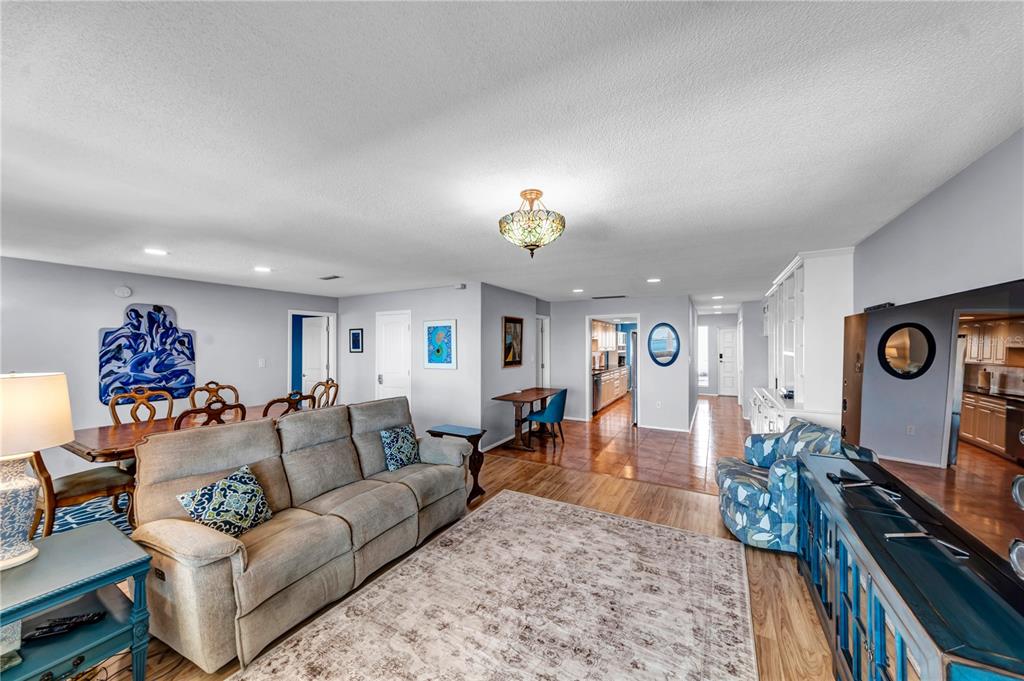 A living room with a beige sofa, dining area, and tile and wood flooring — 622 EDGEWATER DRIVE UNIT 823, DUNEDIN, FL