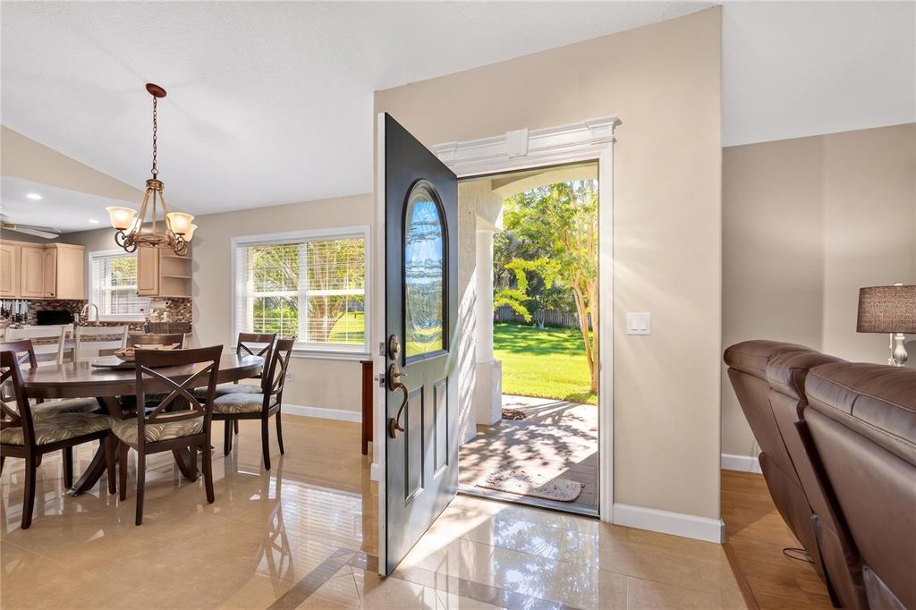 An open front door reveals a view of a green lawn from a tiled dining area — 19923 W ELDORADO DRIVE, EUSTIS, FL