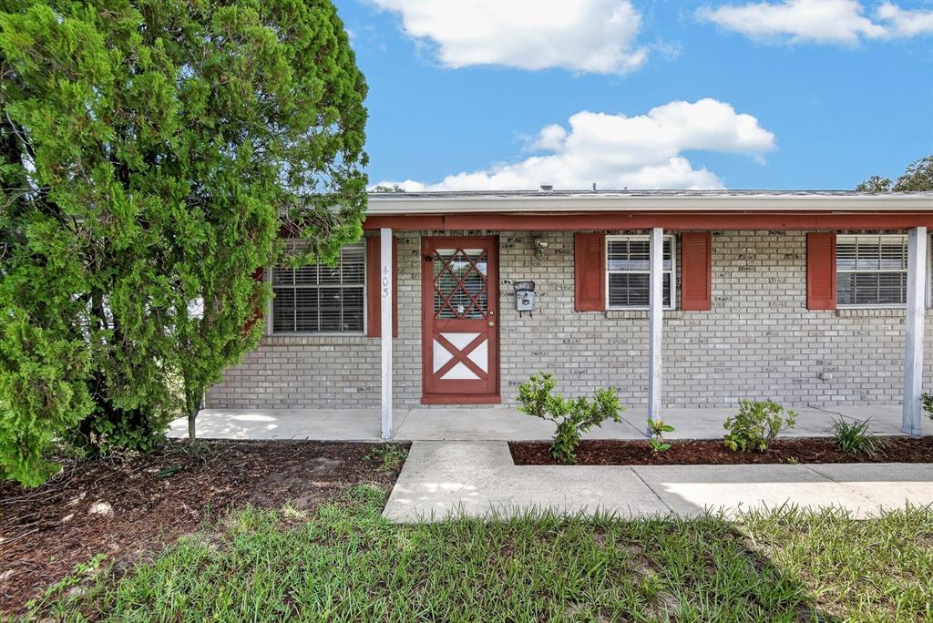 A single-story brick house features a red front door, shutters, and a covered porch — 403 ALMA DRIVE, BRANDON, FL